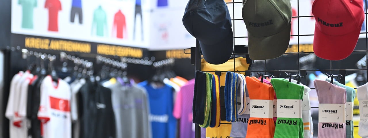 promotional caps, socks, and apparel at a trade fair booth at PROMOGIFT
