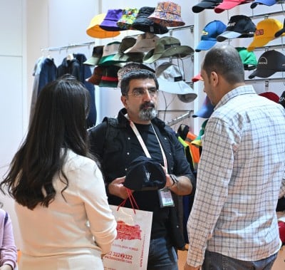 Alıcılar, PROMOGIFT İstanbul ticaret fuarında tanıtım pazarlaması için markalı şapkaları inceliyor.