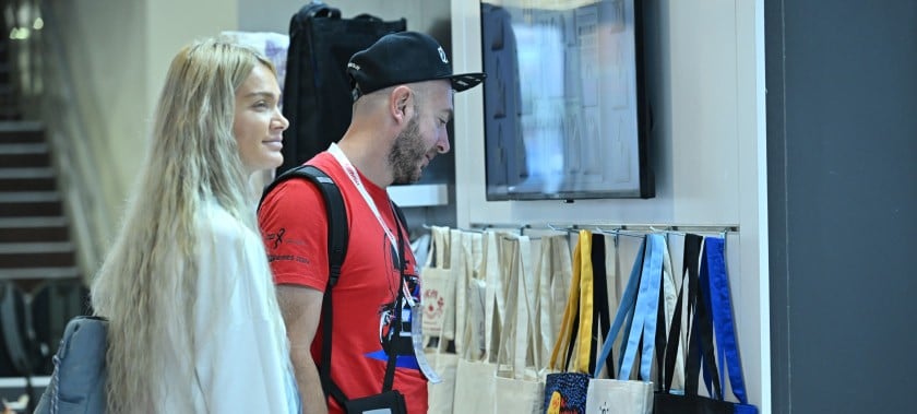 Ziyaretçiler, PROMOGIFT İstanbul tanıtım ürünleri fuarında çevre dostu bez çantaları inceliyor.